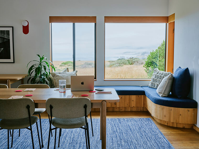 Working space with a bench by the corner of windows and a table and chairs